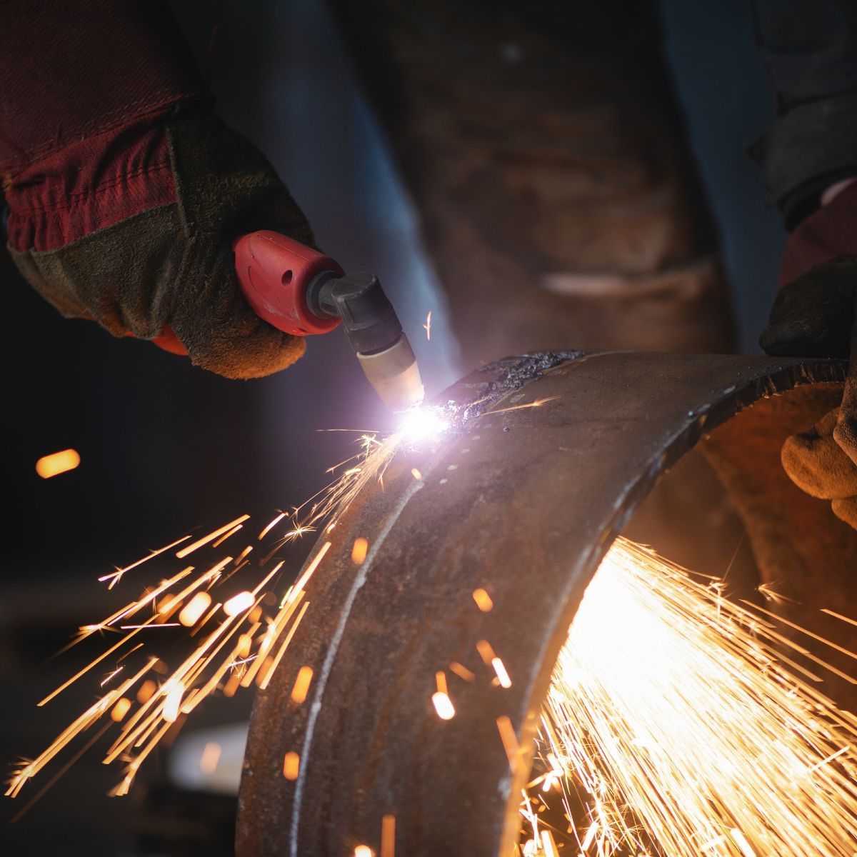 A person is cutting a piece of metal with sparks coming out of it