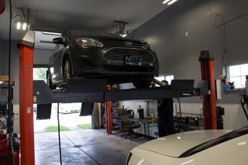 Black car raised on a vehicle lift inside an auto repair shop