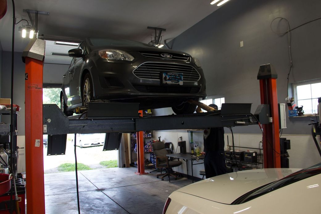 Interior bay showing Ford sedan on hydraulic lift with clean bay walls and professional equipment