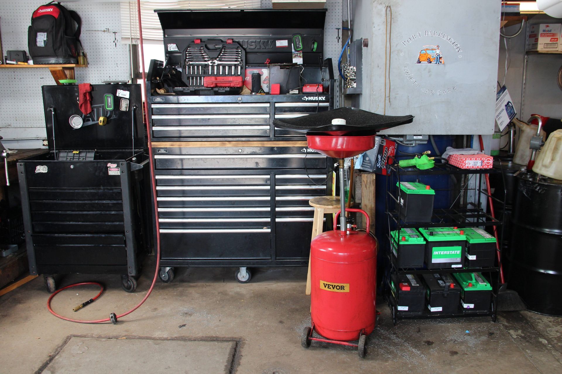 Professional shop equipment including Husky tool chest, oil drain unit, and Interstate Batteries rack