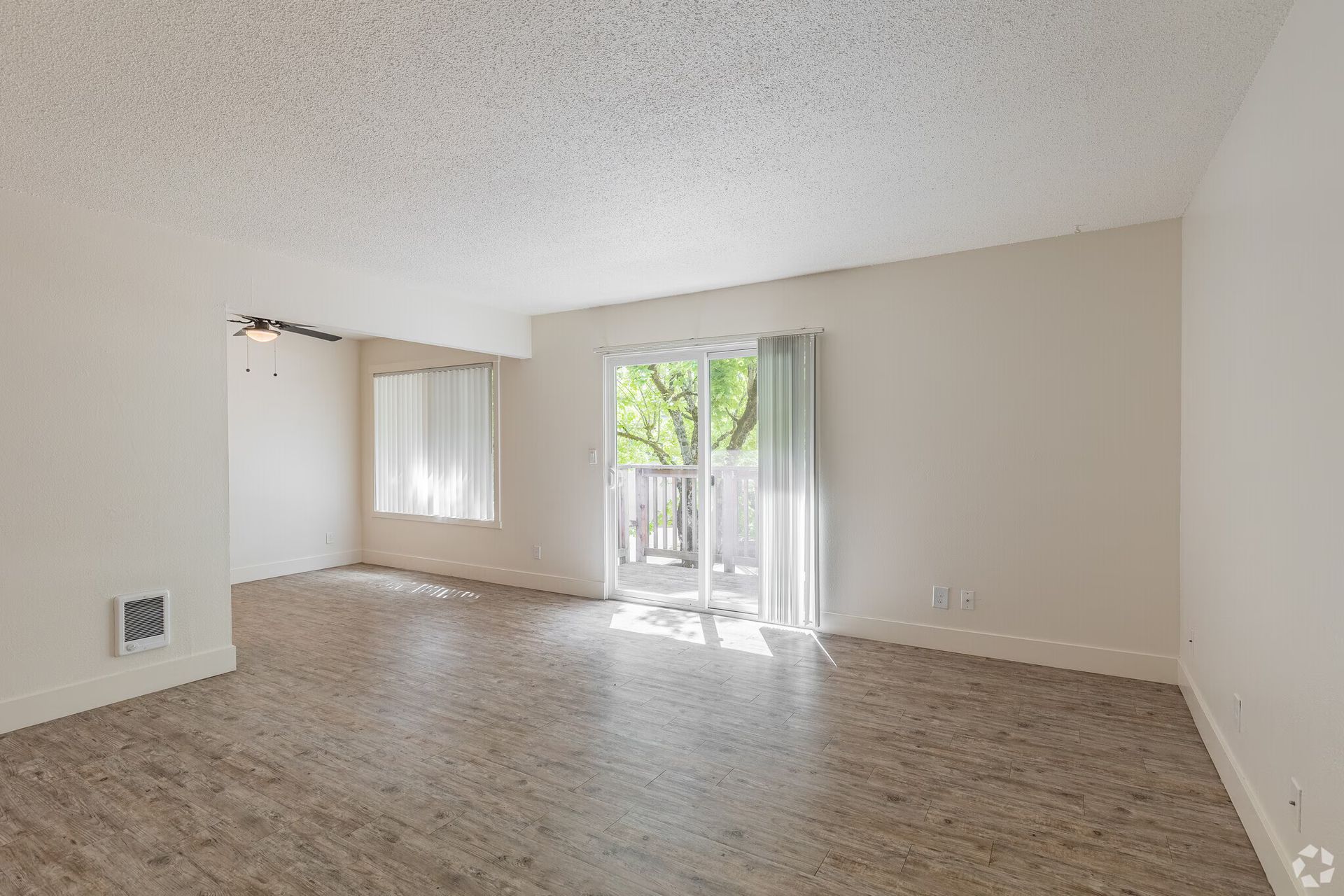 Empty beige living room with sliding glass doors and carpeted floor