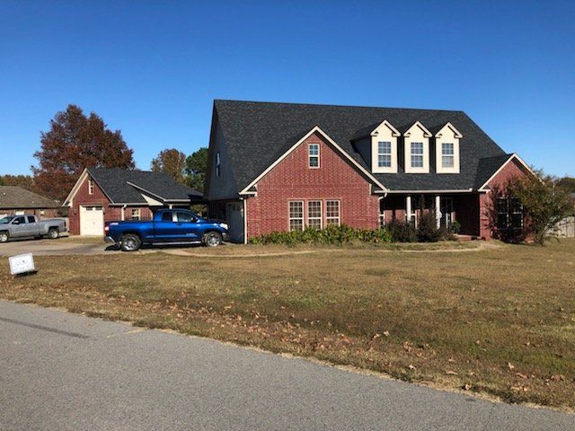 A blue truck is parked in front of a large brick house