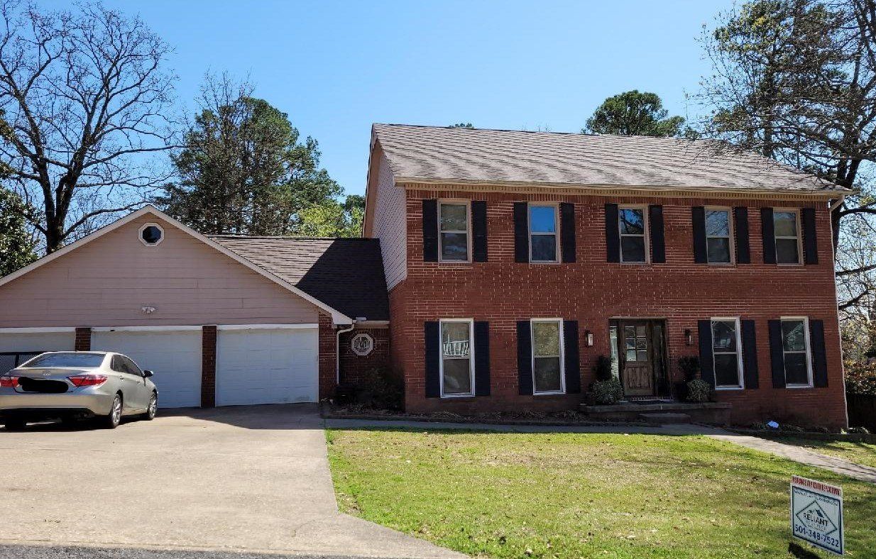 A brick house with a car parked in front of it