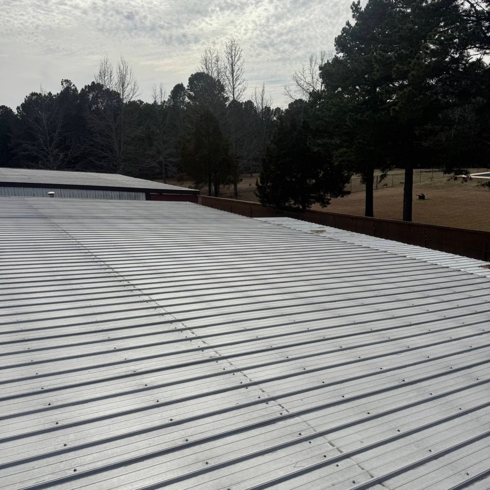 Worker using a yellow nail gun to install gray shingles on a roof