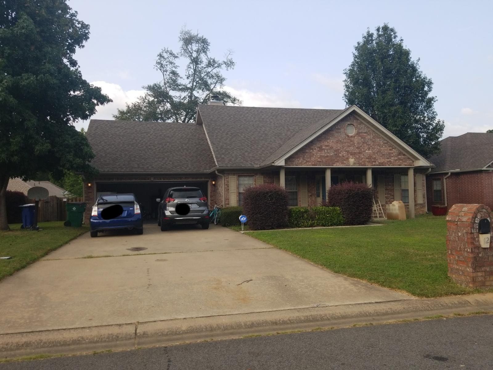A blue car is parked in front of a brick house