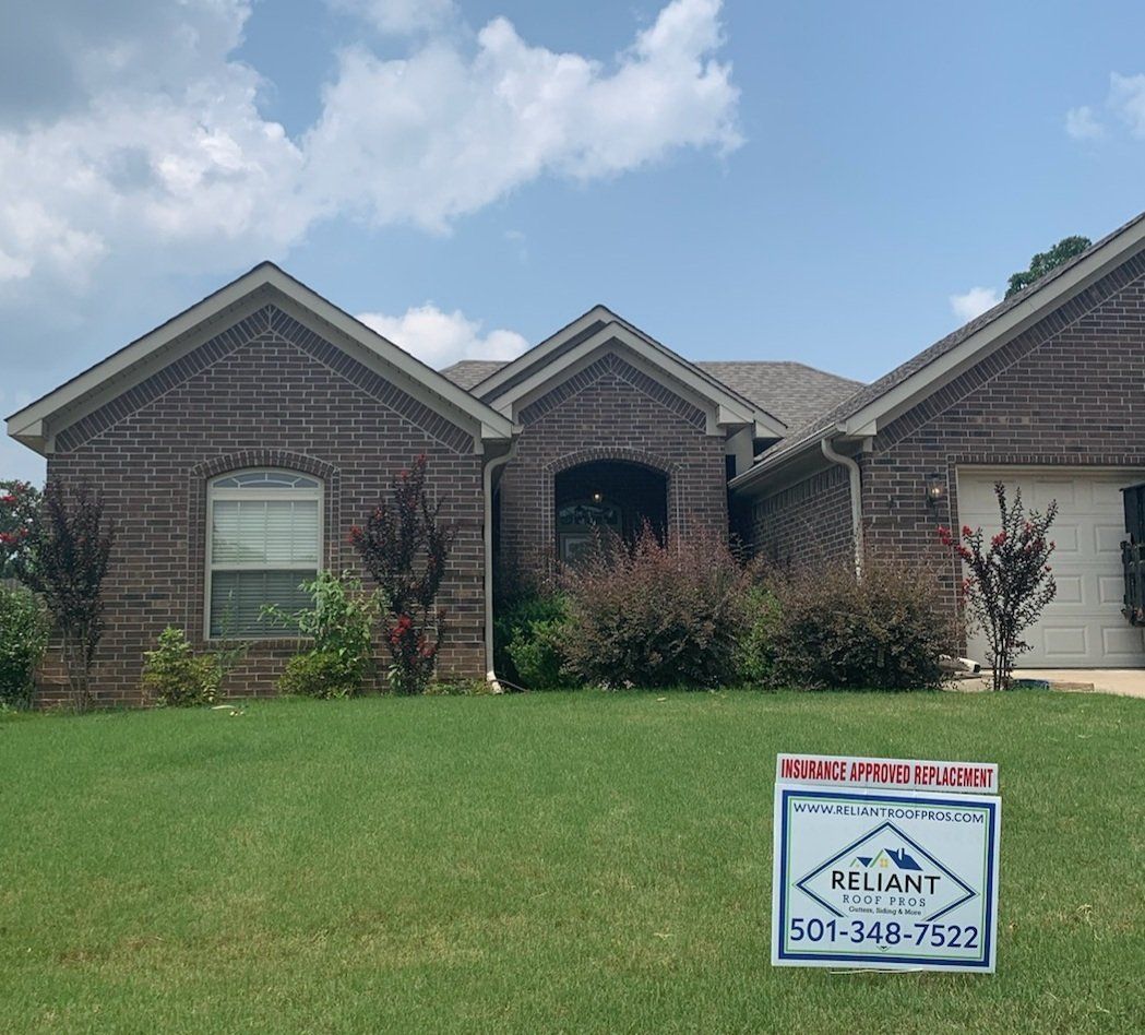 A brick house with a sign in front of it.