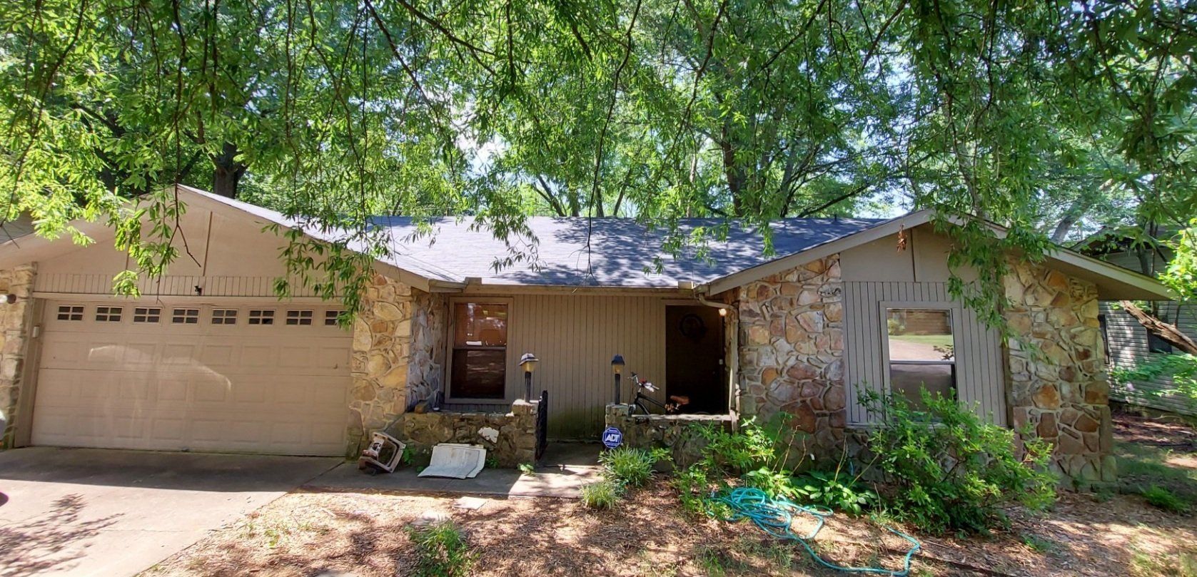 A house with a garage door and a tree in front of it.