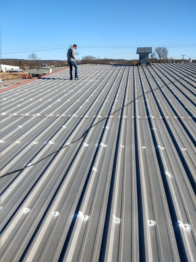A man is standing on top of a metal roof.