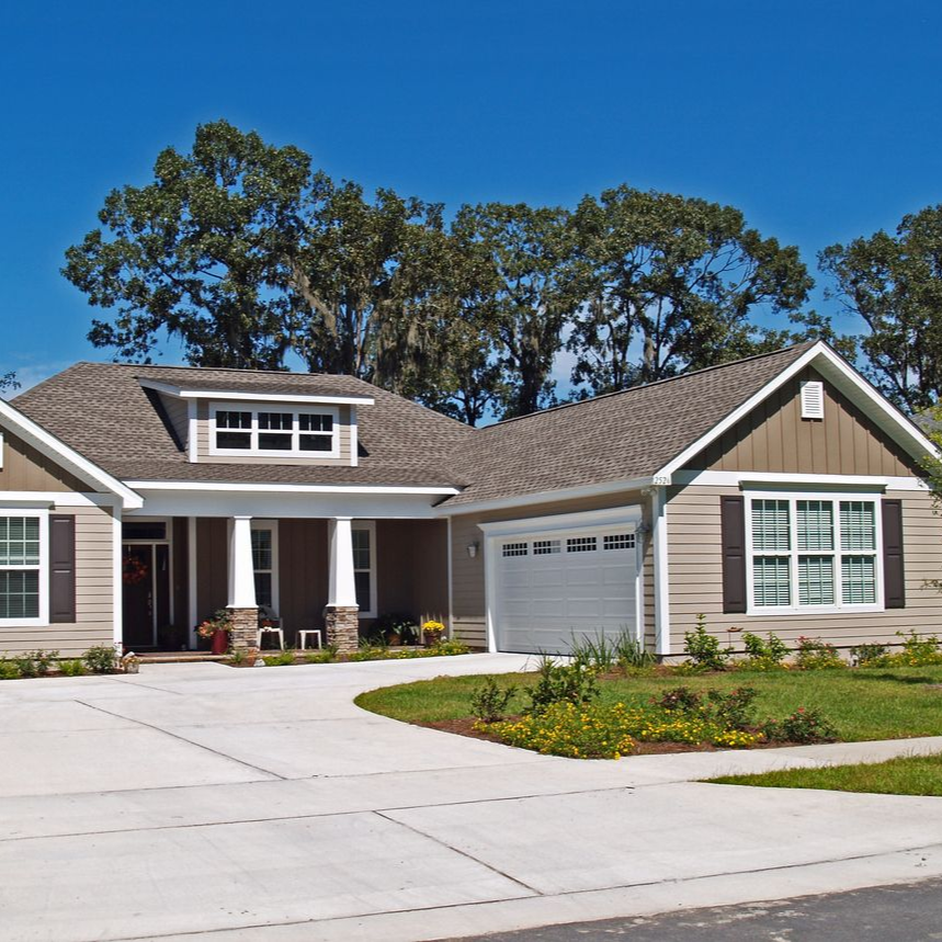 Single-story suburban house with a two-car garage, driveway, and landscaped front yard under a blue sky