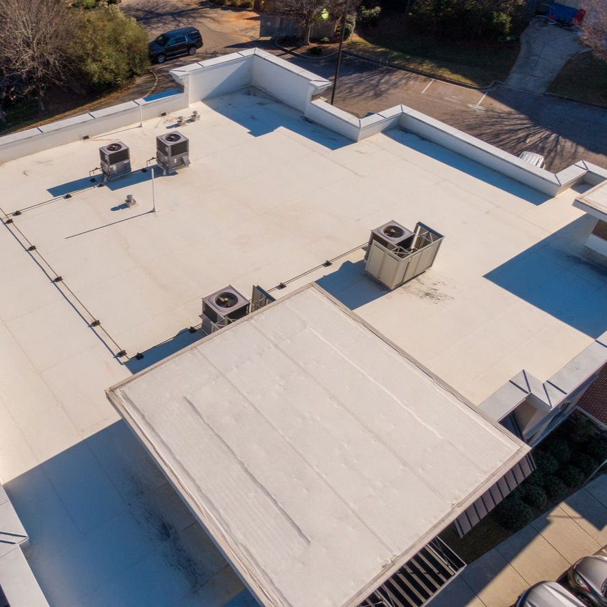 Worker using a yellow nail gun to install gray shingles on a roof