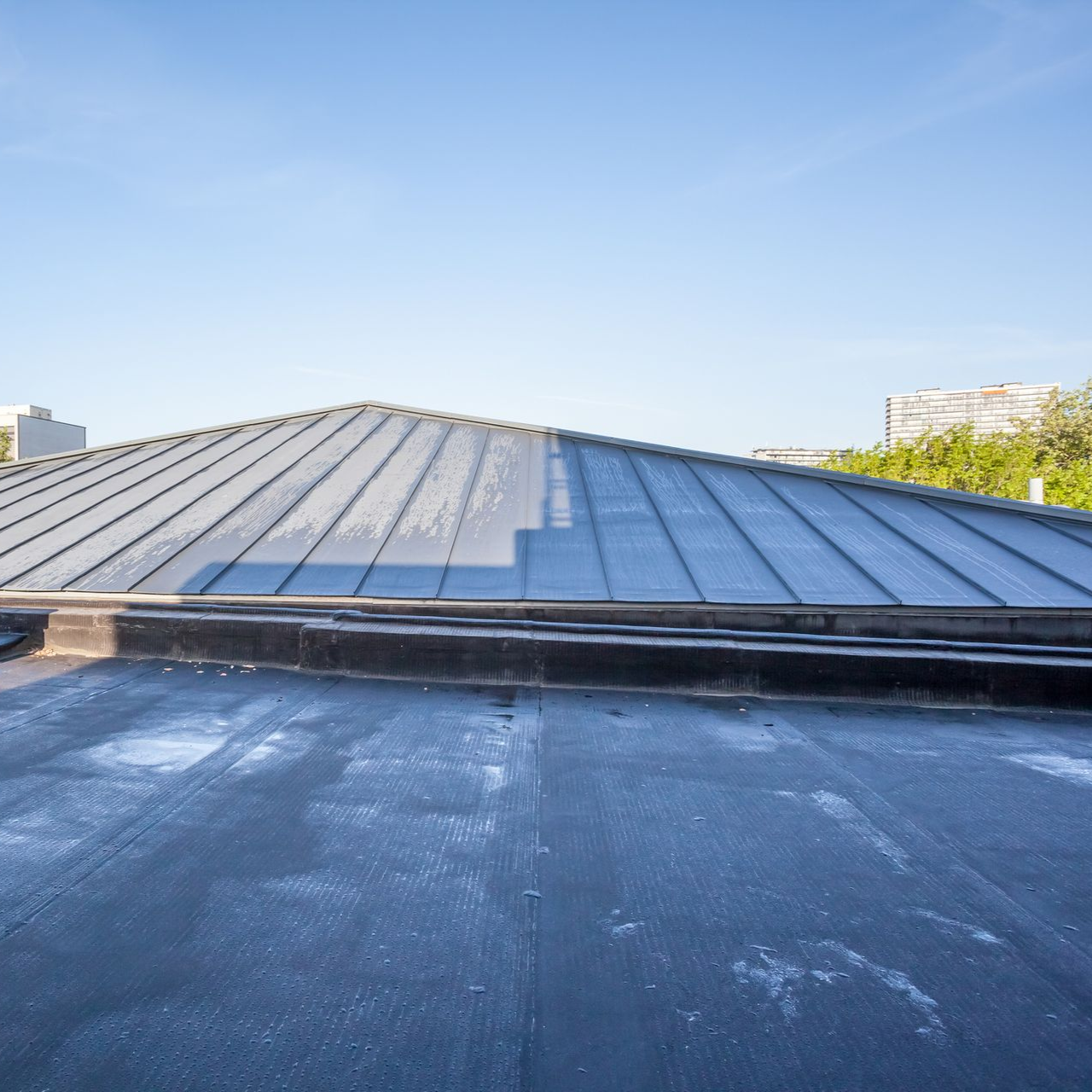 Rooftop with a sloped metal skylight under a clear blue sky