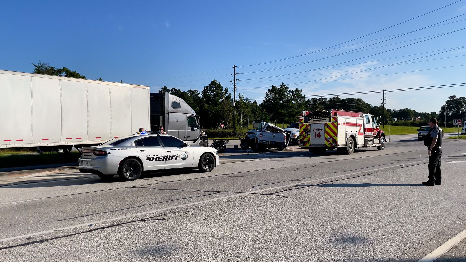Police and emergency vehicles blocking a highway crash scene with responders nearby