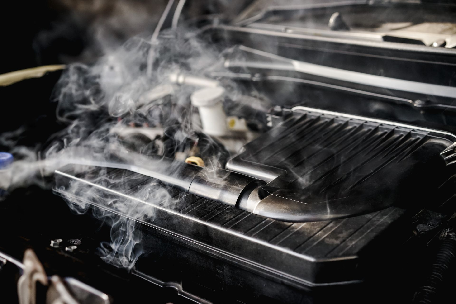 Car engine with steam or smoke rising from the open hood and engine bay