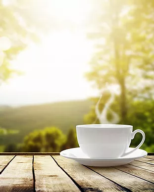 A cup of coffee is sitting on a wooden table.