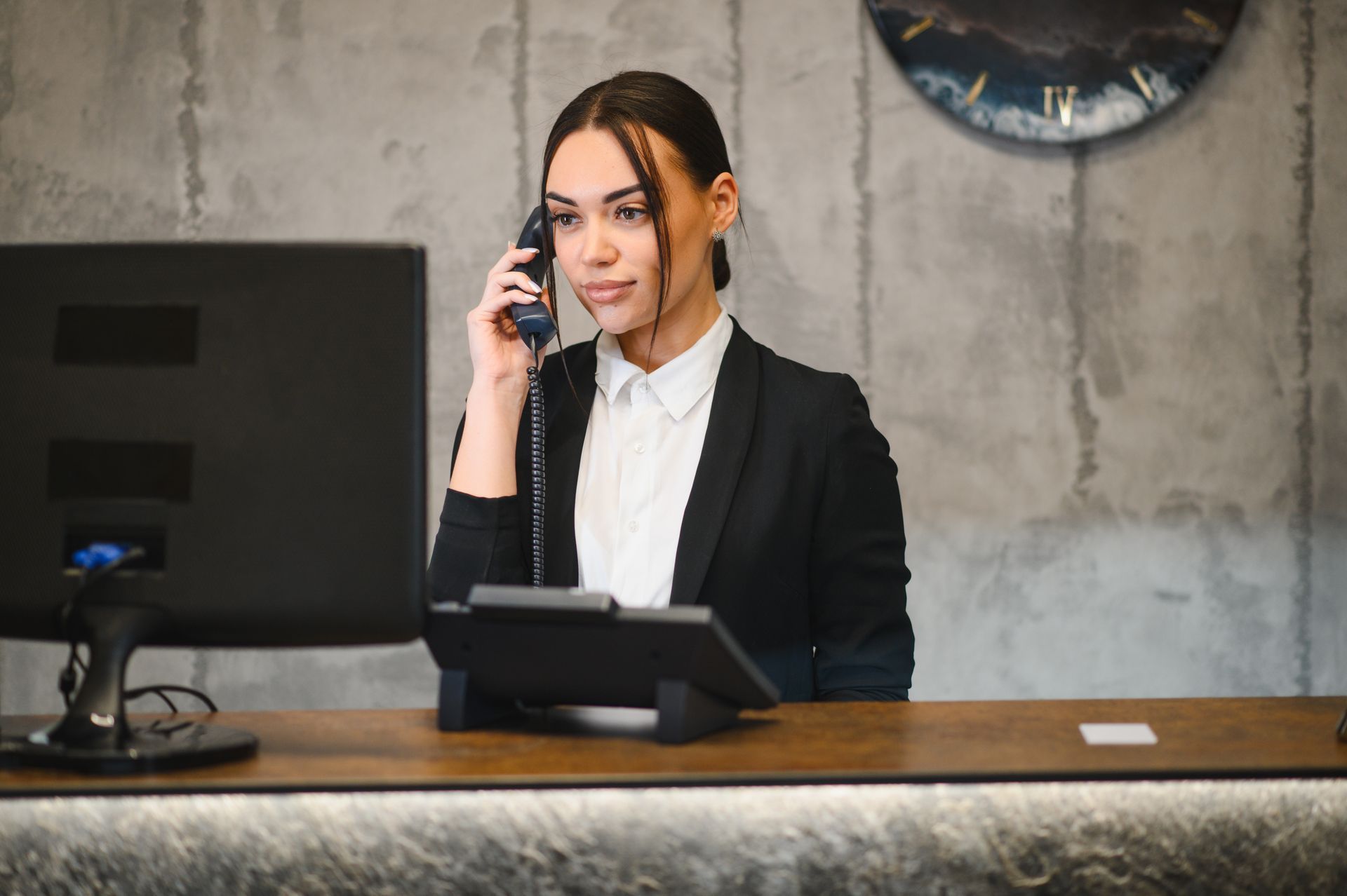 Receptionist speaking on the phone behind a desk in a modern office lobby