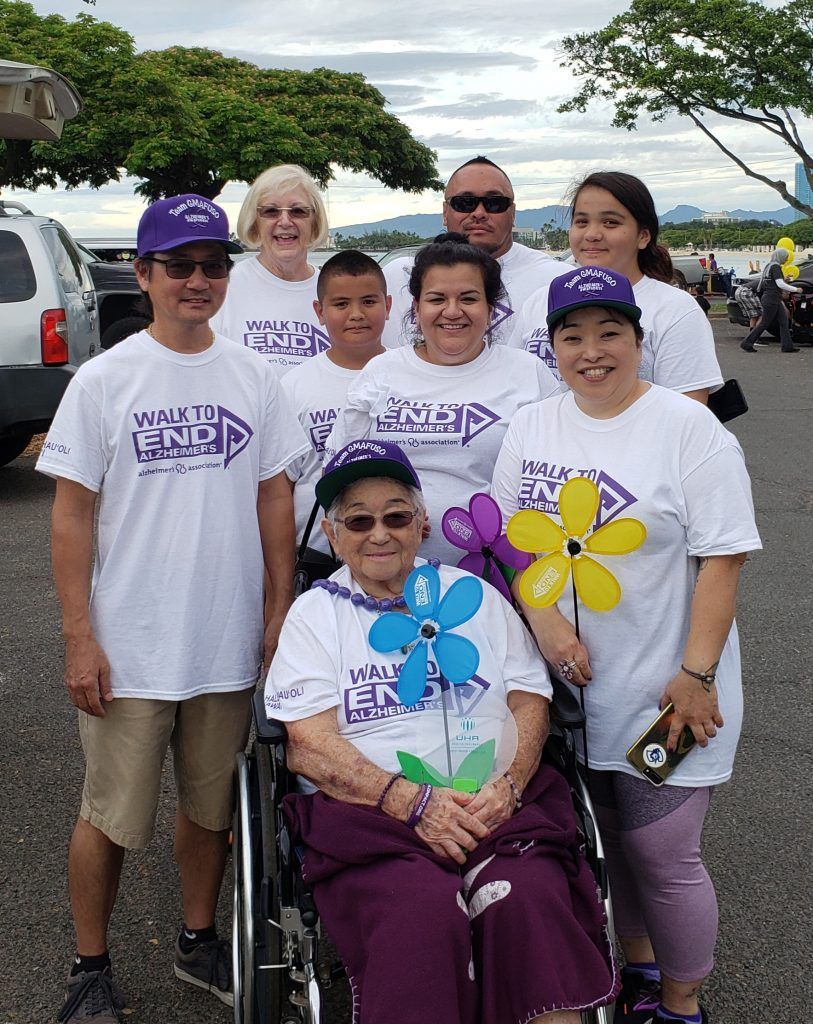 A group of people are posing for a picture with one woman in a wheelchair.