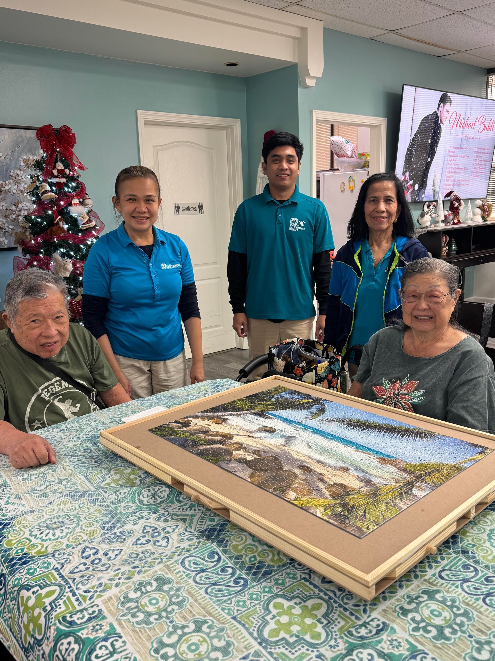 Smiling seniors and caregivers gather around a table displaying a finished jigsaw puzzle.