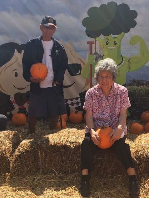 A man and a woman are holding pumpkins in a pumpkin patch