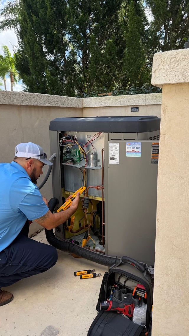Technician kneels beside an open outdoor HVAC unit, using tools to inspect wiring near a stucco wall.