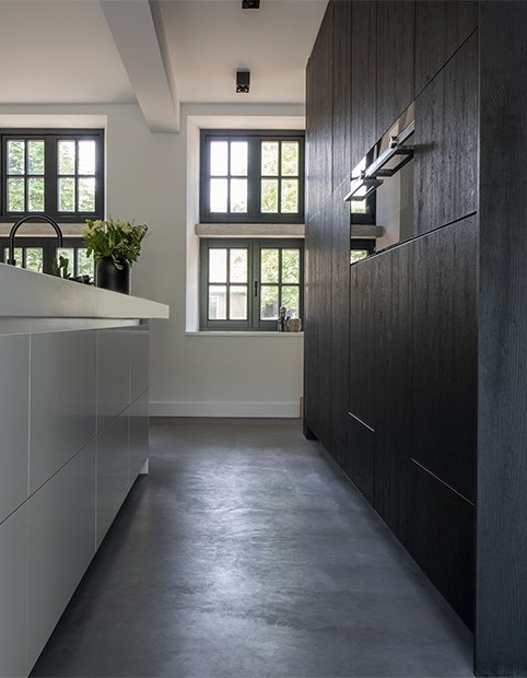 Een keuken met zwarte kasten en roestvrijstalen apparaten