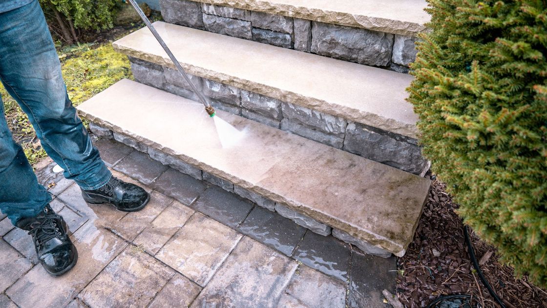 A man is cleaning a set of stairs with a high pressure washer.