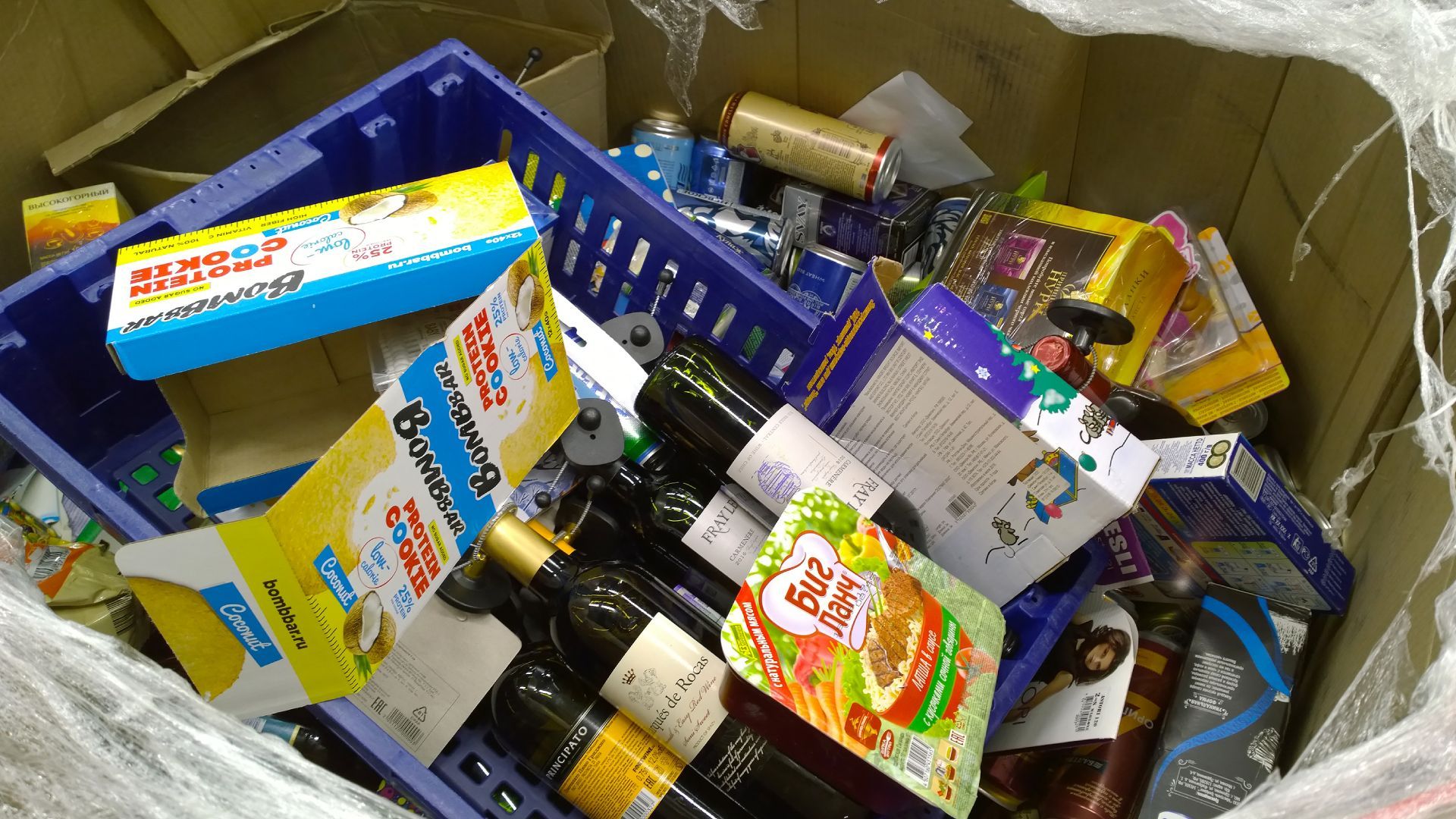 A box filled with bottles and boxes including one that says ' coca cola ' on it