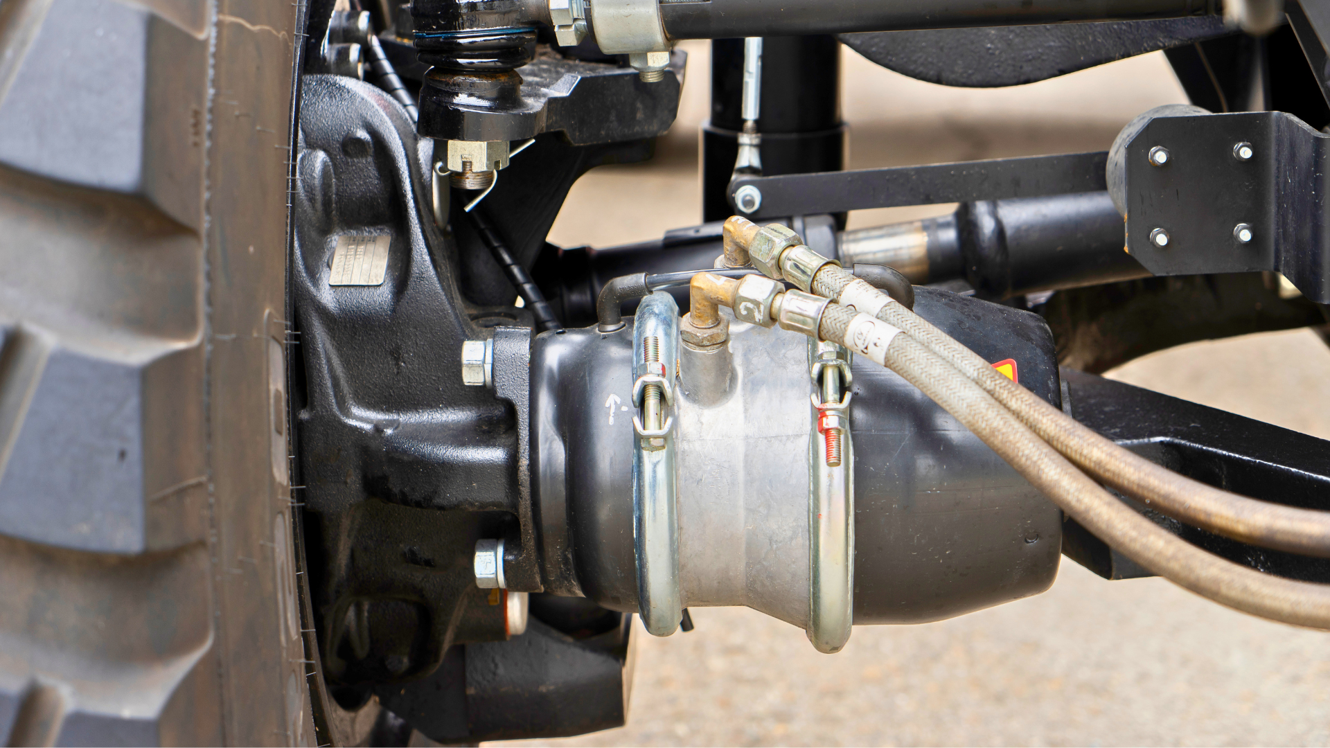 Close-up of a vehicle wheel hub and brake assembly with hoses and metal fittings.