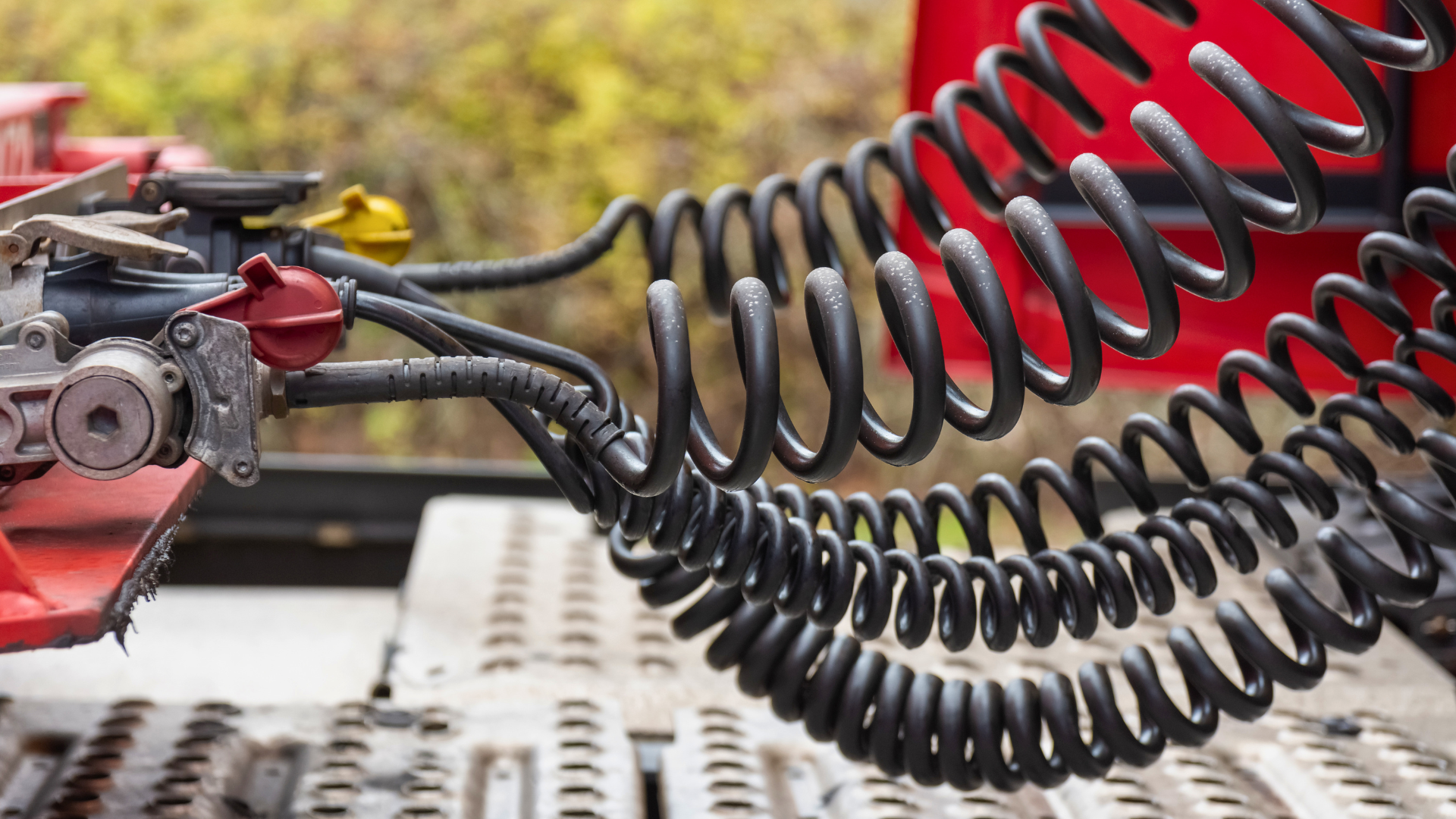Close-up of a red vehicle's coiled air hose and hitch connection on a truck bed