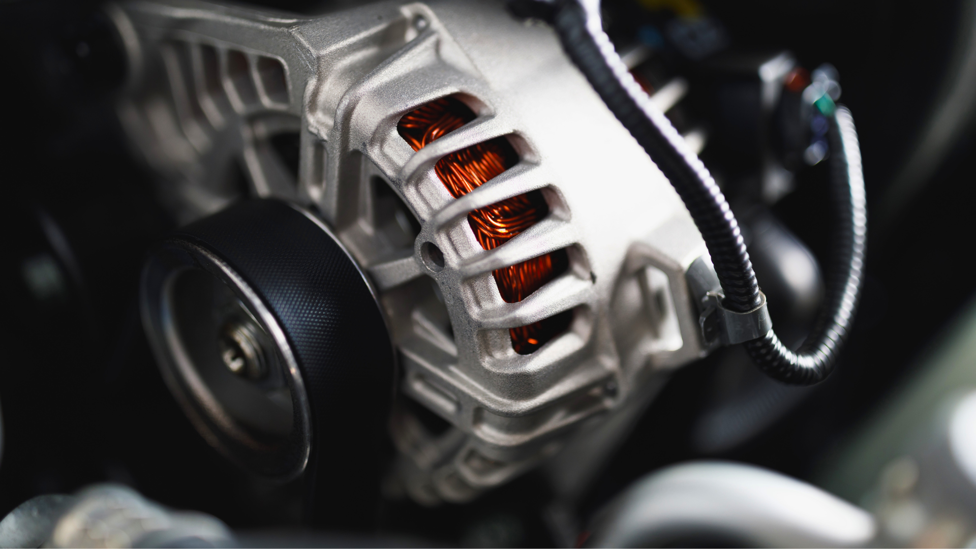 Close-up of a car engine alternator with visible copper coils and black belt components