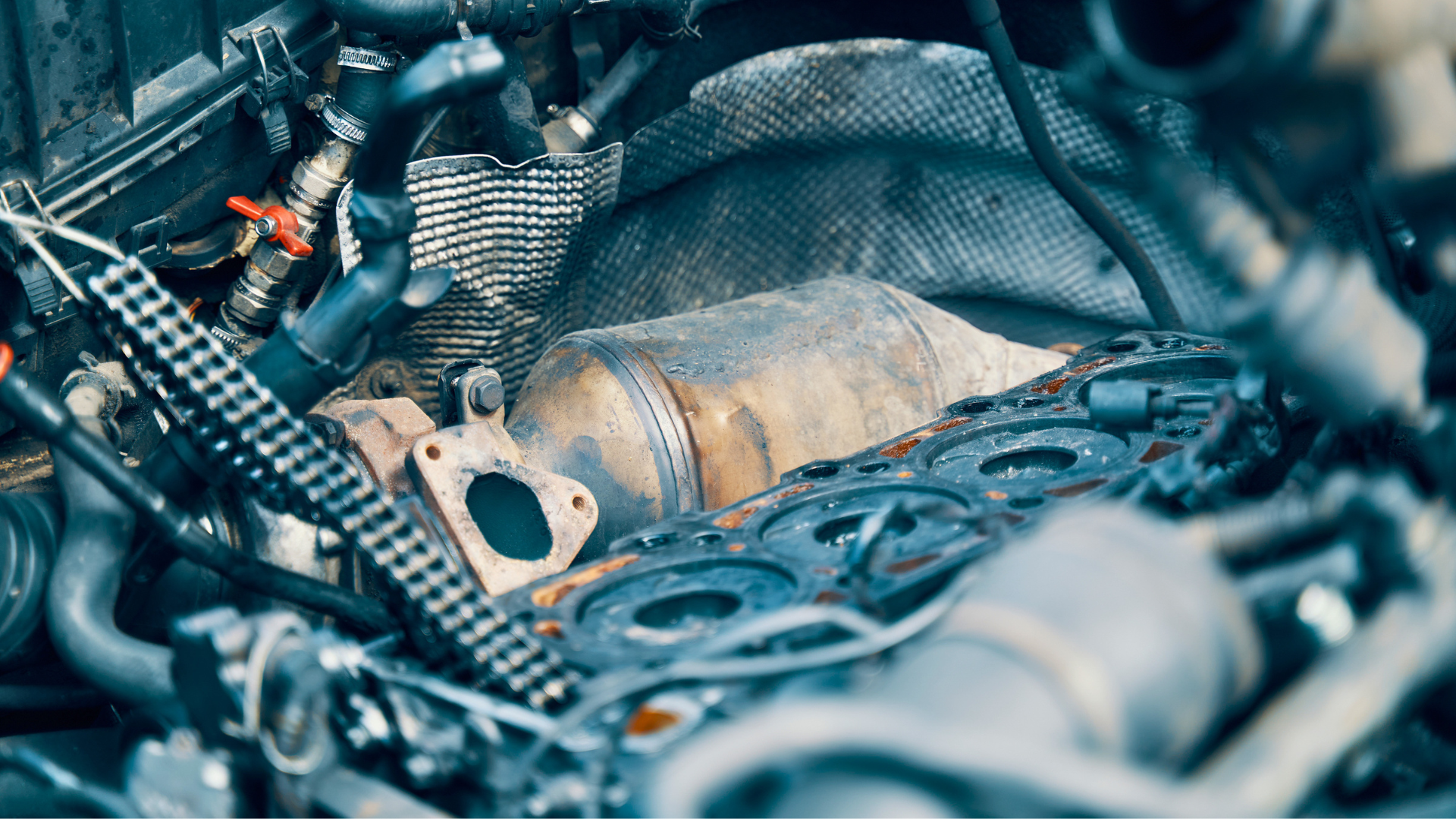 Close-up of a dusty mechanical engine part tangled with black hoses and wires