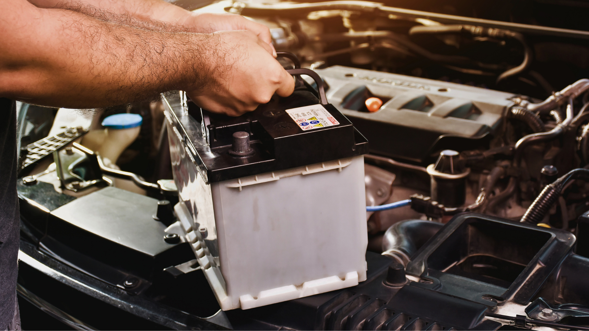 Mechanic wearing gloves uses a wrench to work on a car engine in a garage