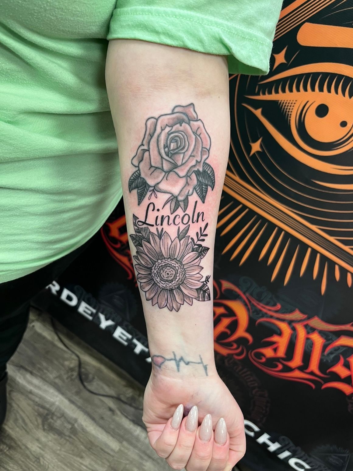 Tattoo on arm: rose and sunflower above