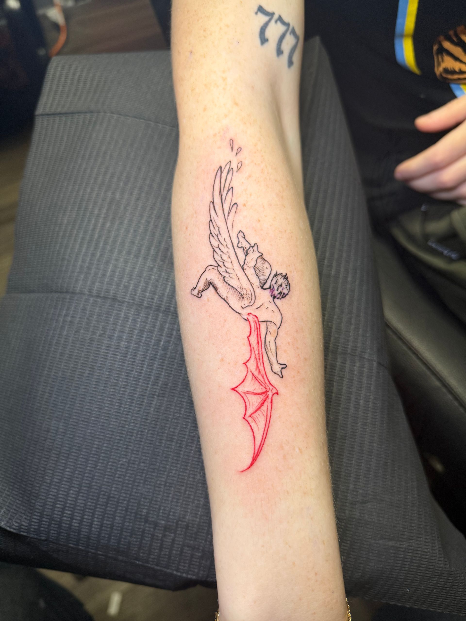 Arm tattoo: Falling angel transforming into a red devil.