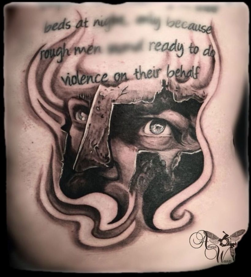 Tattoo of a Spartan warrior's face, with a quote about violence. Black and white.