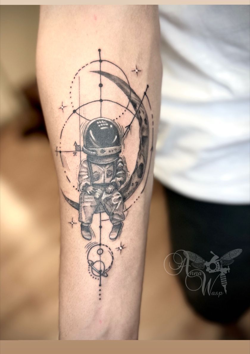 Tattoo of an astronaut sitting on a crescent moon, surrounded by geometric lines and stars.
