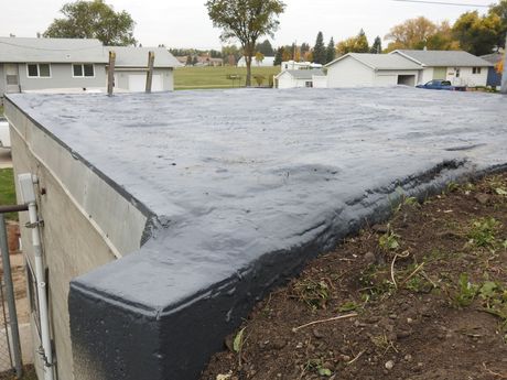 Flat rooftop with dark grey coating; houses in background.