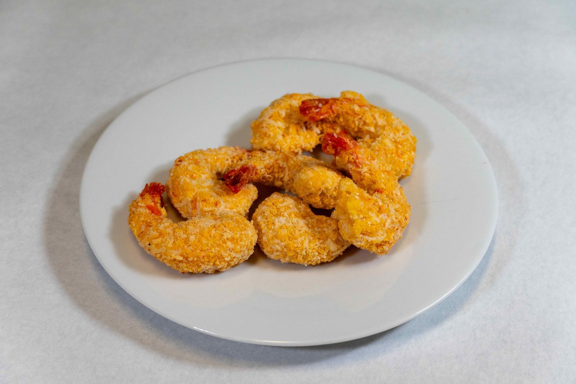 Une assiette blanche garnie de crevettes frites sur une table.