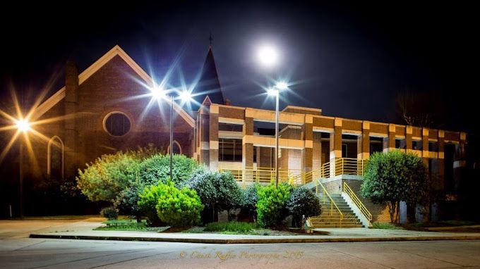 A church with a steeple is lit up at night