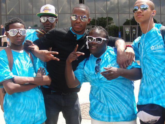 A group of young men wearing tie dye shirts are posing for a picture