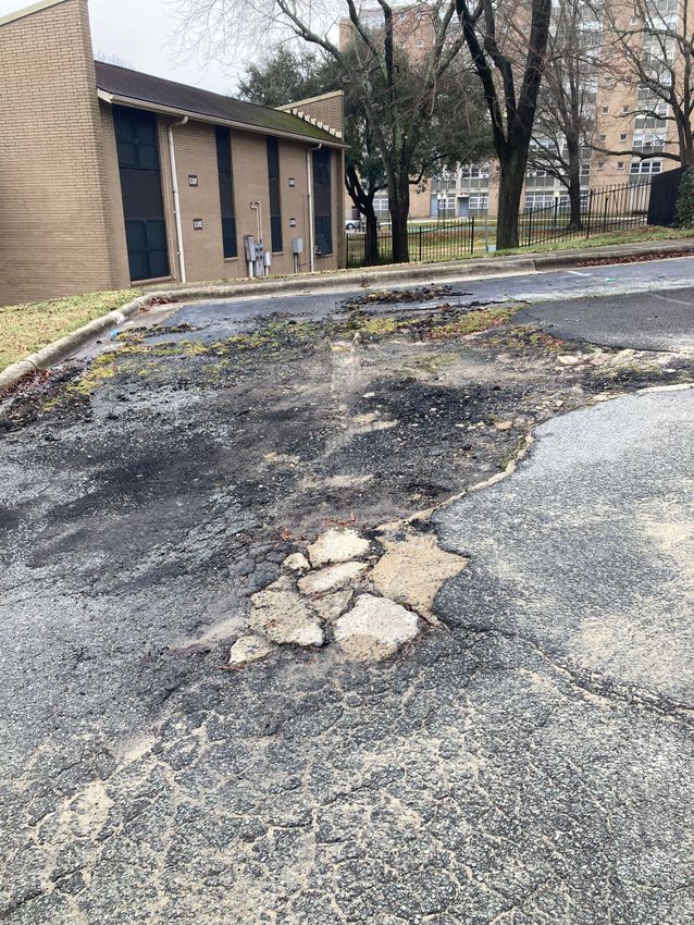 A very dirty parking lot with a building in the background.