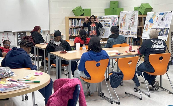 A group of people are sitting at tables in a classroom.