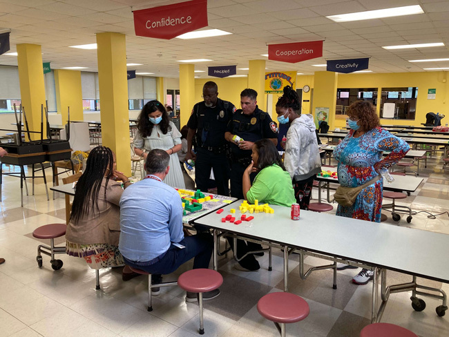 A group of people are sitting at tables in a cafeteria.