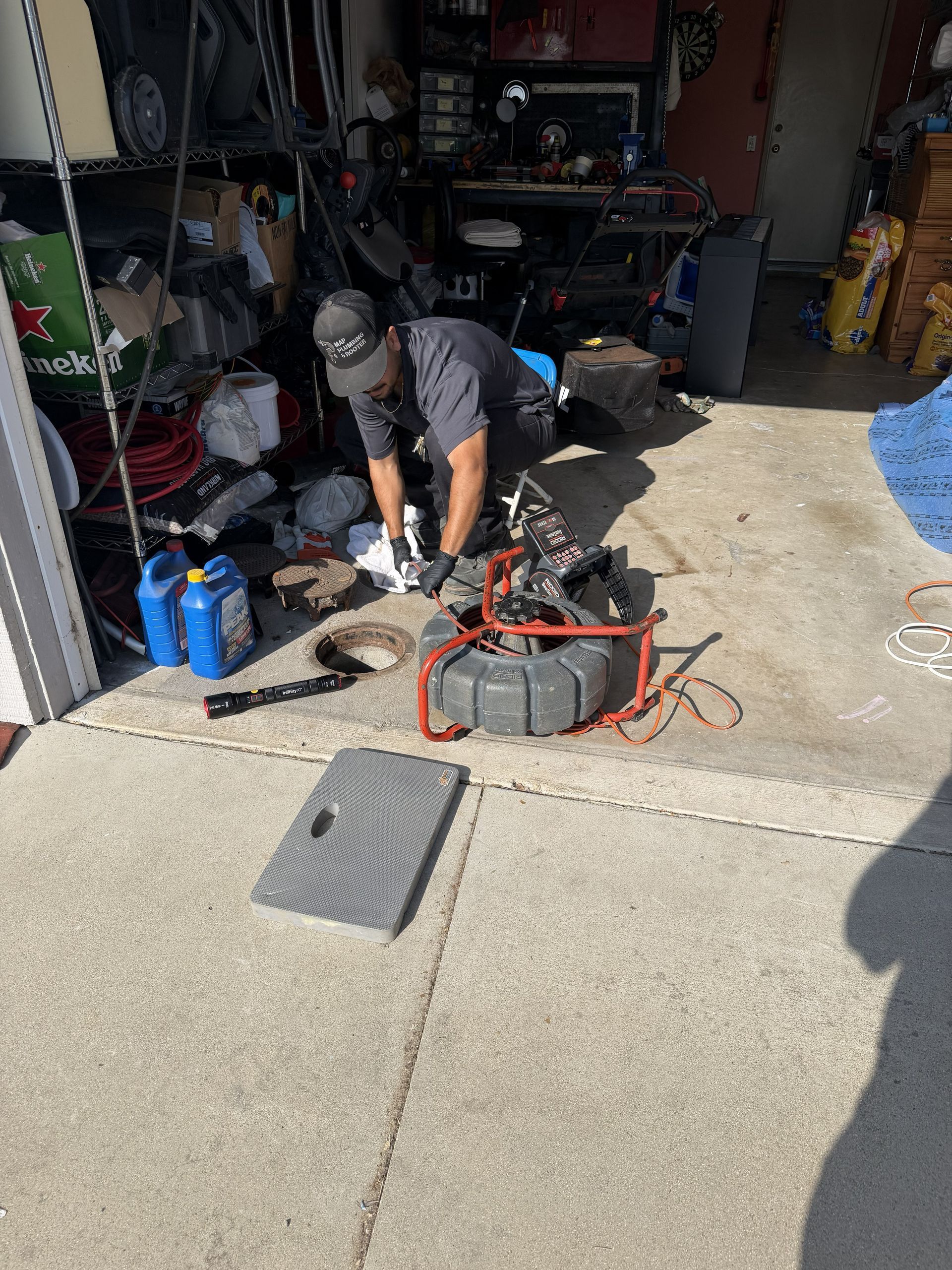Person kneeling in a garage, working on a red motorcycle amid tools and equipment.