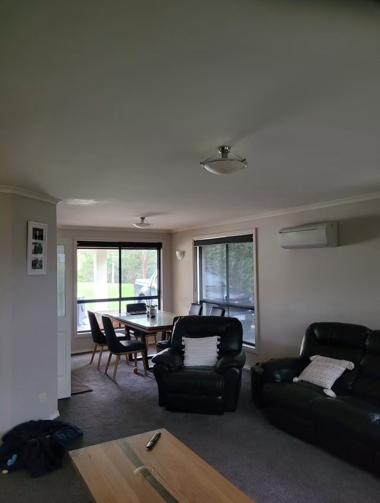 Living room with black sofa and chairs, ceiling fans, wall AC, and sliding glass door to a patio.