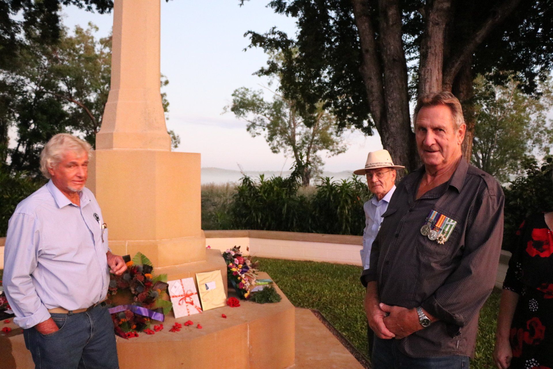 Three men are standing in front of a stone monument