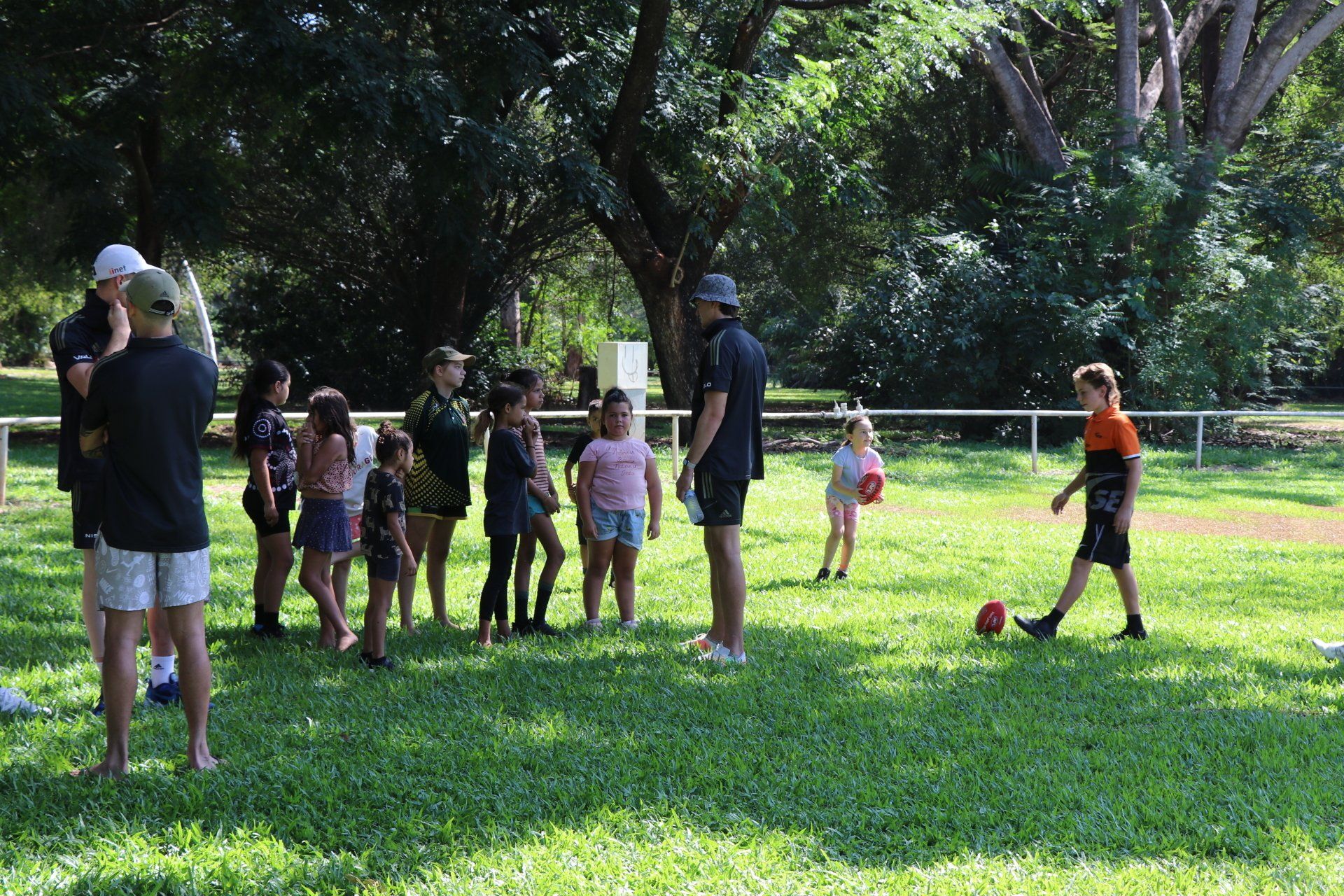 A group of people are standing on top of a lush green field.