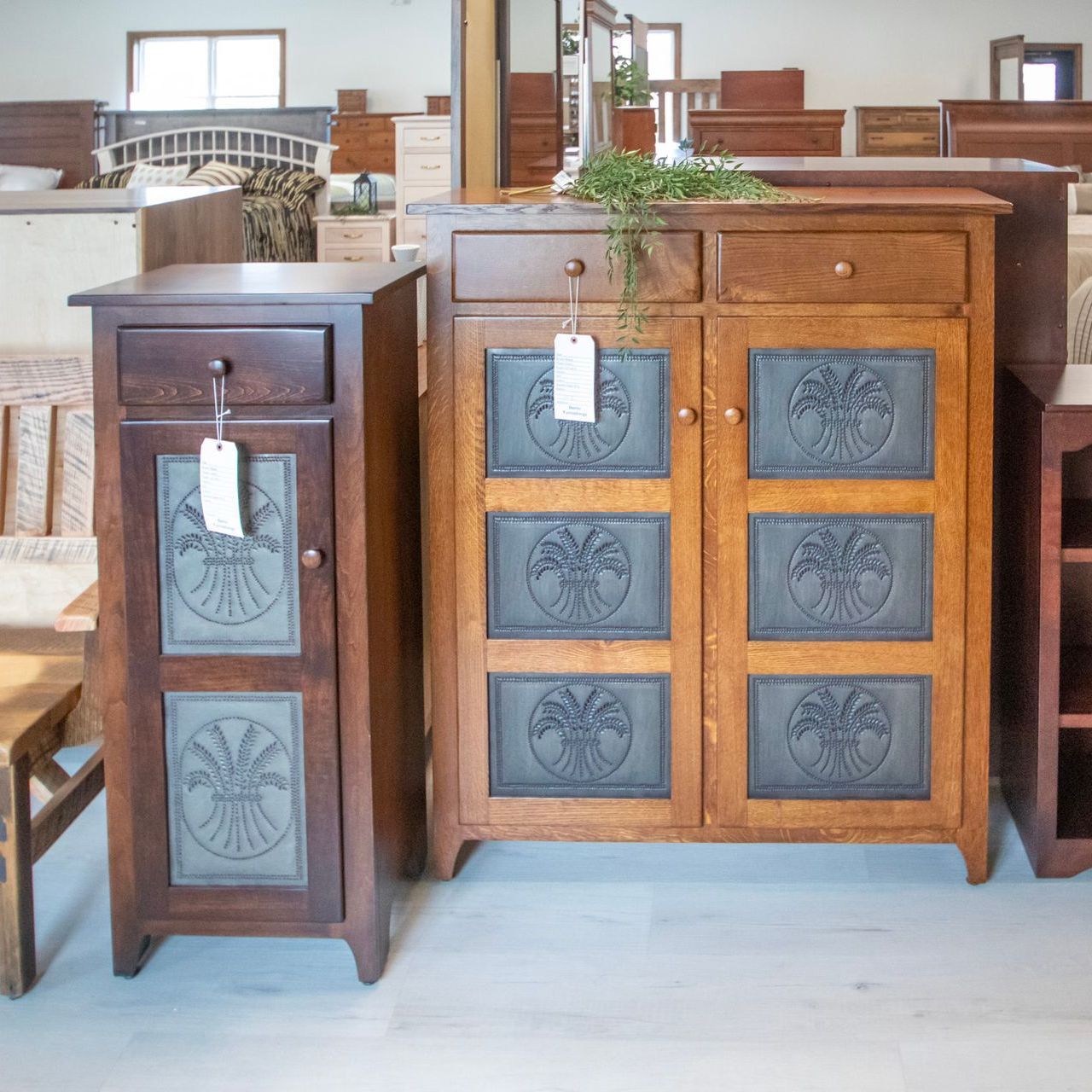 Wooden cabinets with metal tree designs on doors, in a furniture store.