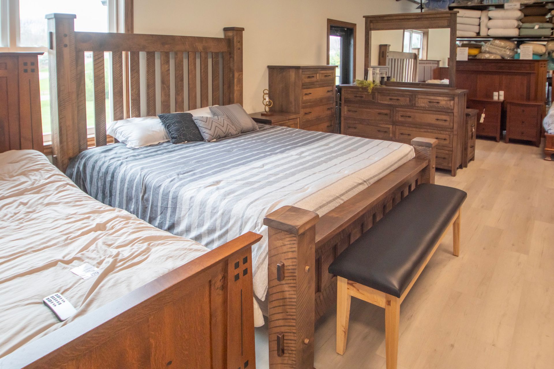 Bedroom furniture display featuring wooden beds, dresser, and mirror.