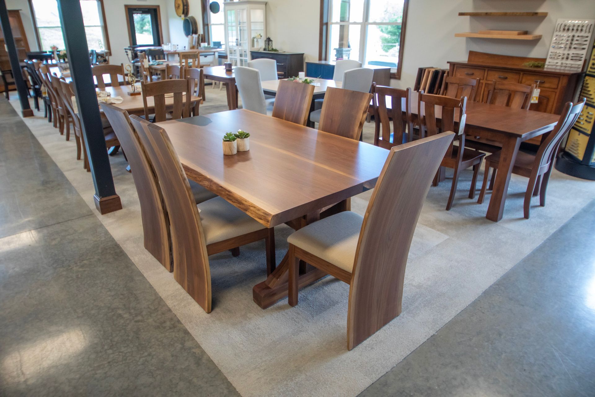 A furniture showroom displays various wooden dining tables and chairs.