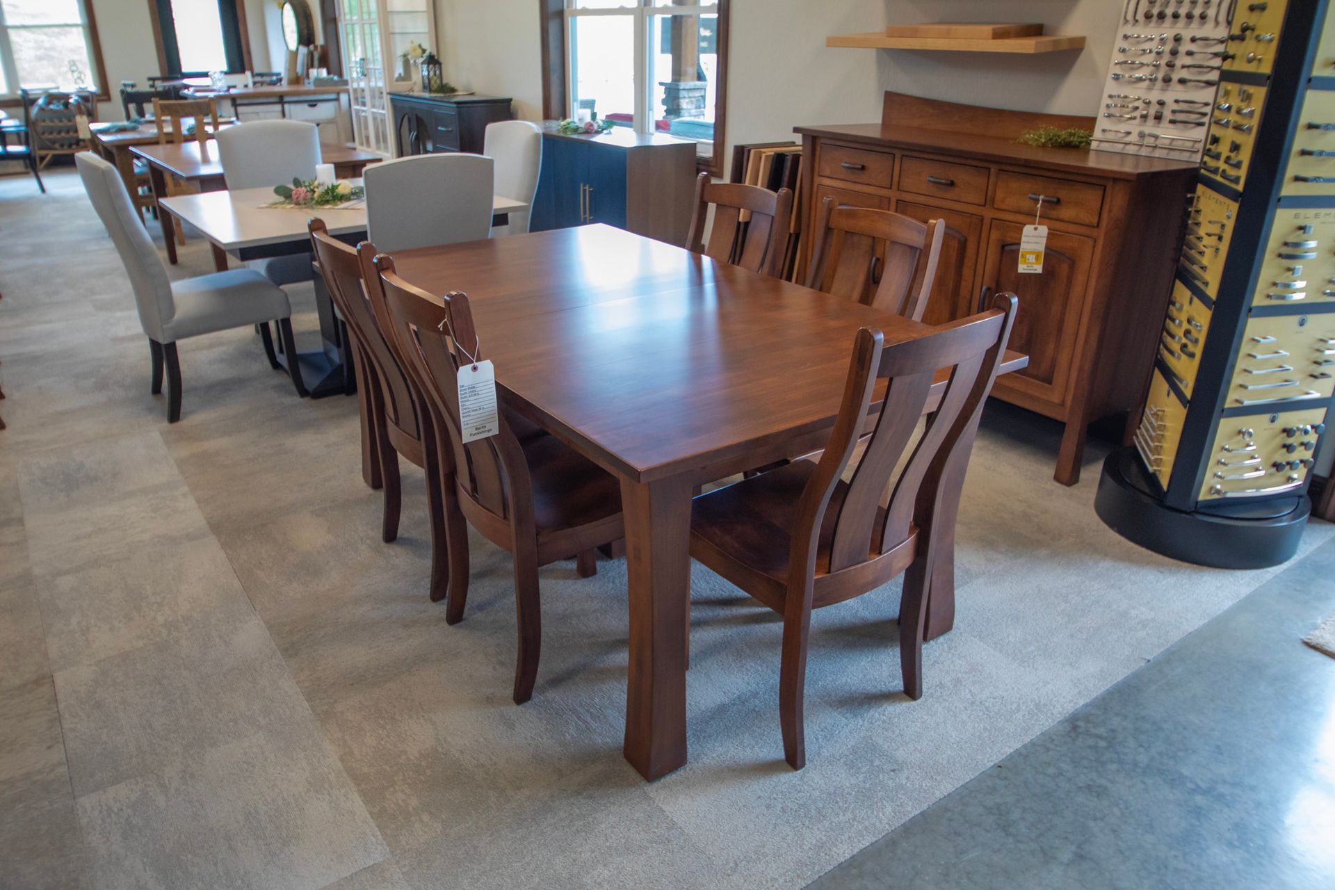 Wooden dining table with six matching chairs in a furniture showroom.
